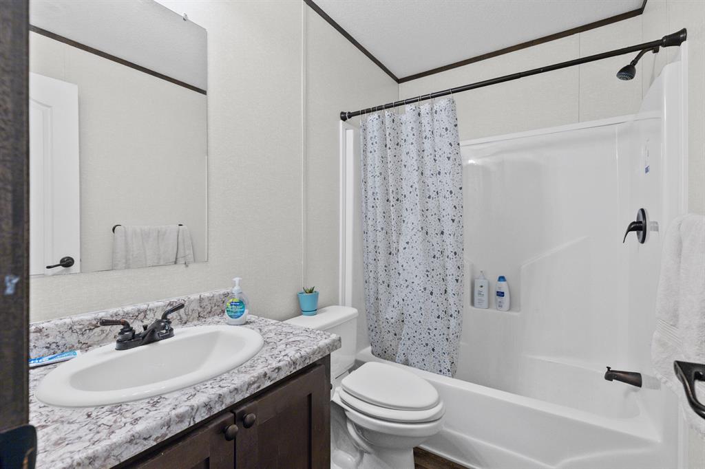 Bathroom featuring a vanity with a patterned countertop, integrated basin, matte black faucet, wall-mounted mirror, and a shower-tub combination with matching matte black fixtures