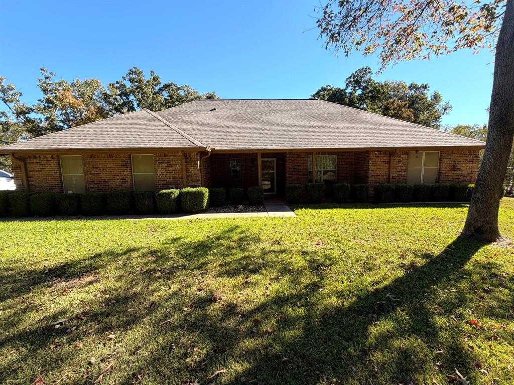 Single-story brick exterior featuring a hip roof, covered entryway, and manicured landscaping