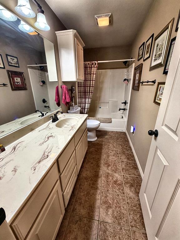 Bathroom featuring a vanity with patterned countertop, integrated oval sink, matte black hardware, and wall-to-wall vanity mirror, paired with a shower-tub combination and tile-finish flooring