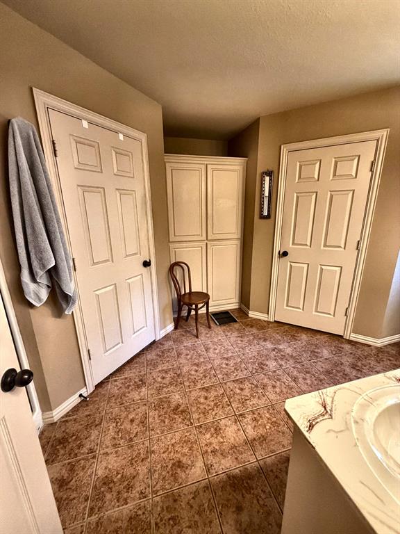 Tile flooring arranged in a diagonal pattern, white six-panel doors, and built-in floor-to-ceiling cabinetry with shaker-style panels