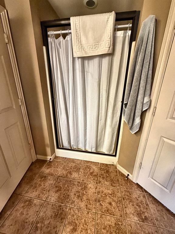 Shower enclosure featuring a dark frame, white tile flooring, and two paneled interior doors