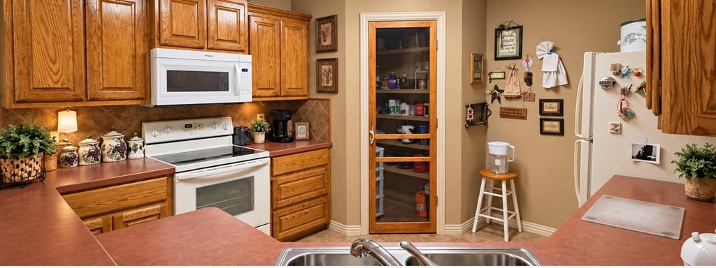 Kitchen featuring wood cabinetry, integrated pantry with a glass-paneled door, stone-finish countertops, and an over-the-range microwave