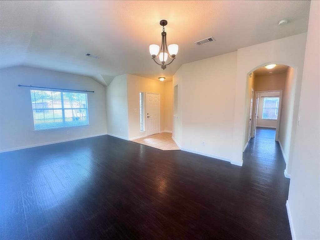 Unfurnished room featuring lofted ceiling, a chandelier, and dark wood-type flooring
