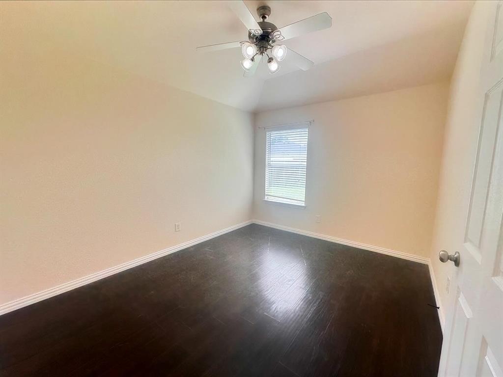 Spare room with vaulted ceiling, ceiling fan, and dark hardwood / wood-style floors