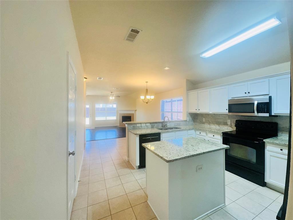 Kitchen featuring sink, decorative light fixtures, kitchen peninsula, a kitchen island, and black appliances