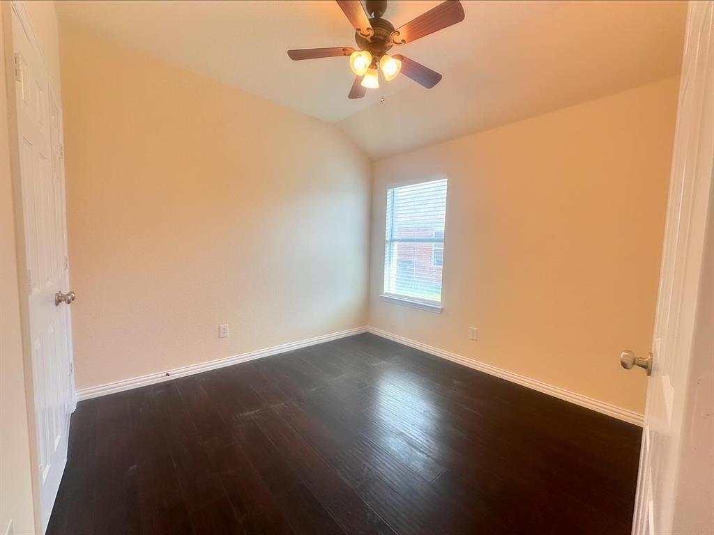 Empty room featuring vaulted ceiling, ceiling fan, and dark hardwood / wood-style flooring