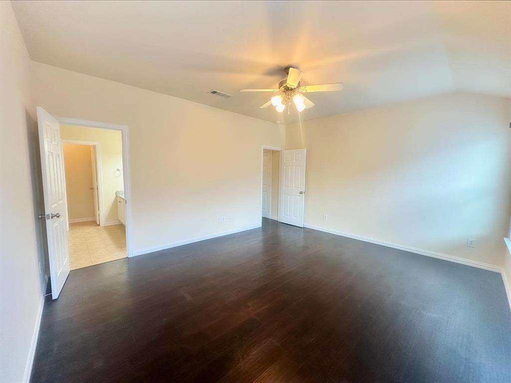 Empty room with ceiling fan, lofted ceiling, and dark wood-type flooring