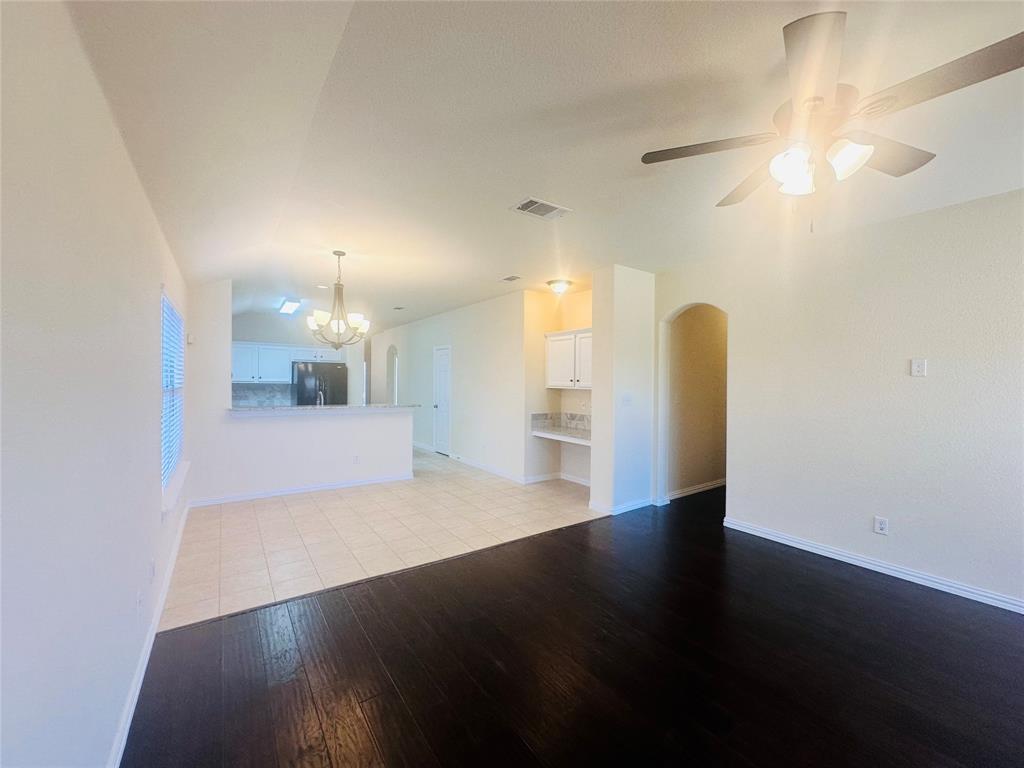 Unfurnished living room with lofted ceiling, ceiling fan with notable chandelier, and light hardwood / wood-style floors