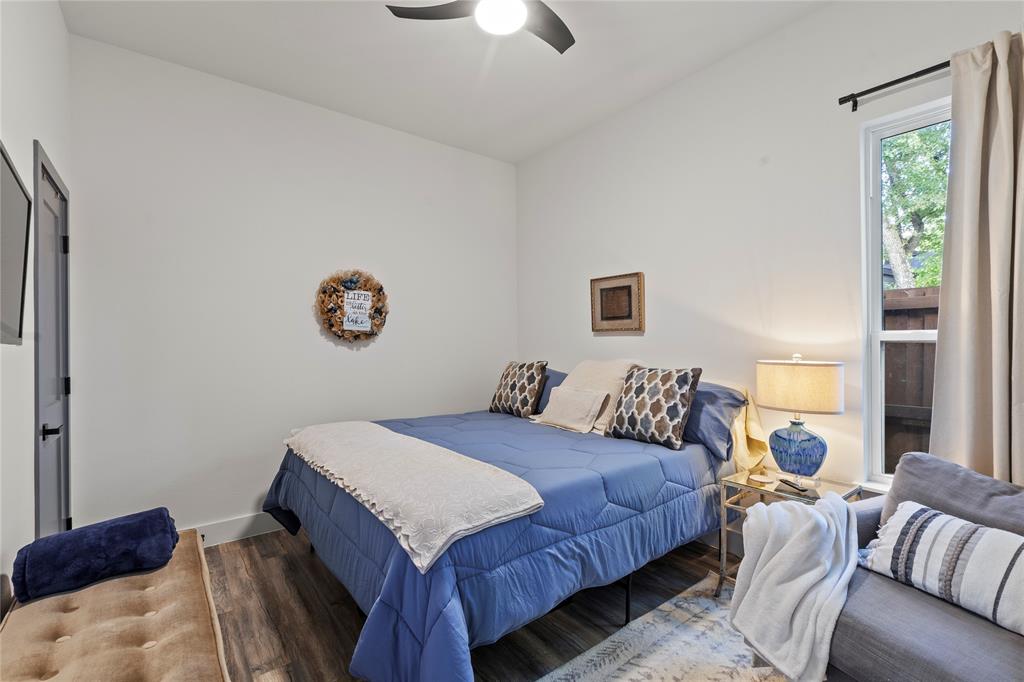 Interior space featuring wood-finish flooring, high ceilings, a contemporary ceiling fan, and a single-hung window with a neutral curtain rod Interior space featuring wood-finish flooring, high ceilings, a contemporary ceiling fan, and a single-hung window with a neutral curtain rod