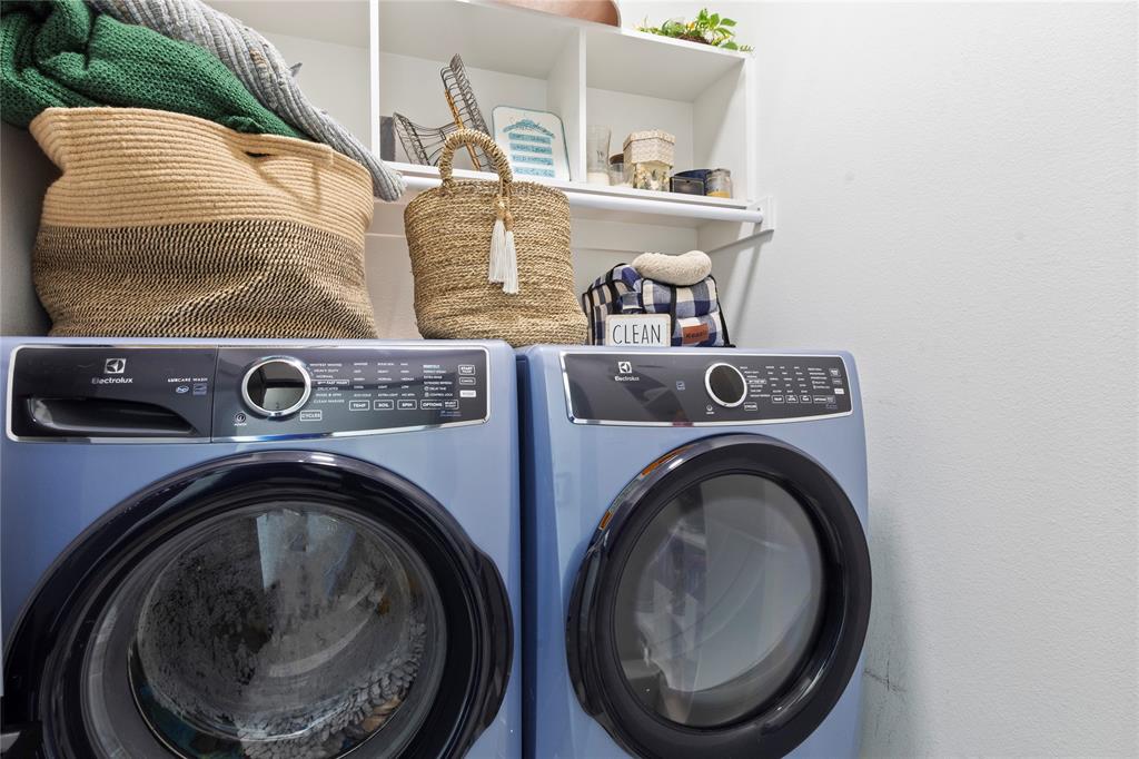 Built-in white open shelving and integrated hanging rod above laundry area