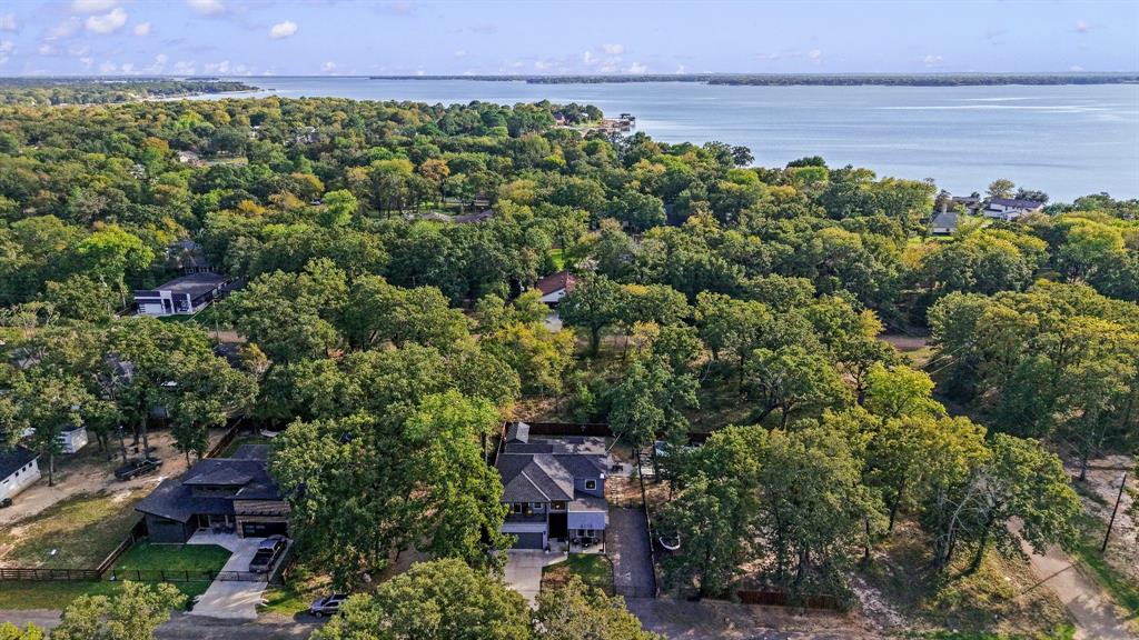 Aerial perspective featuring a multi-story residence with a pitched roof, concrete driveway, and established canopy of mature trees