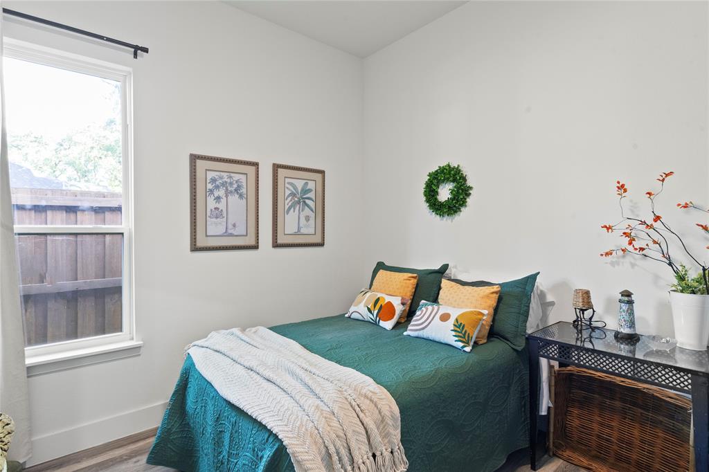 Neutral-toned room featuring a single-hung window with a dark metal curtain rod and wood-finish flooring Neutral-toned room featuring a single-hung window with a dark metal curtain rod and wood-finish flooring