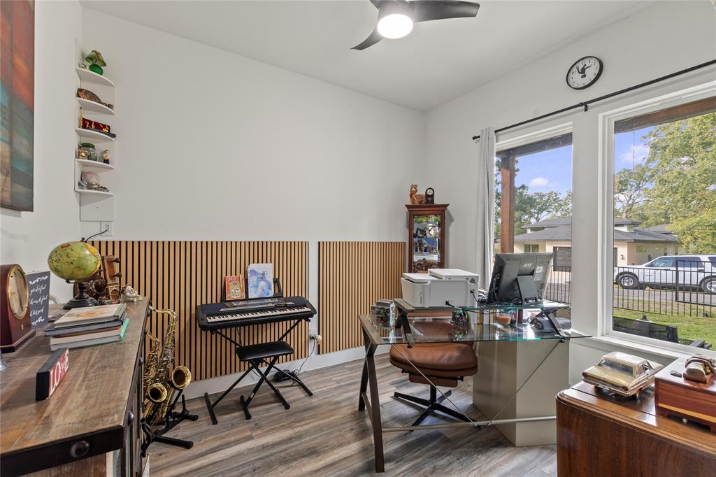 Wood-finish flooring, vertical slat wall paneling, built-in corner shelving, recessed ceiling fan with integrated lighting, and expansive windows