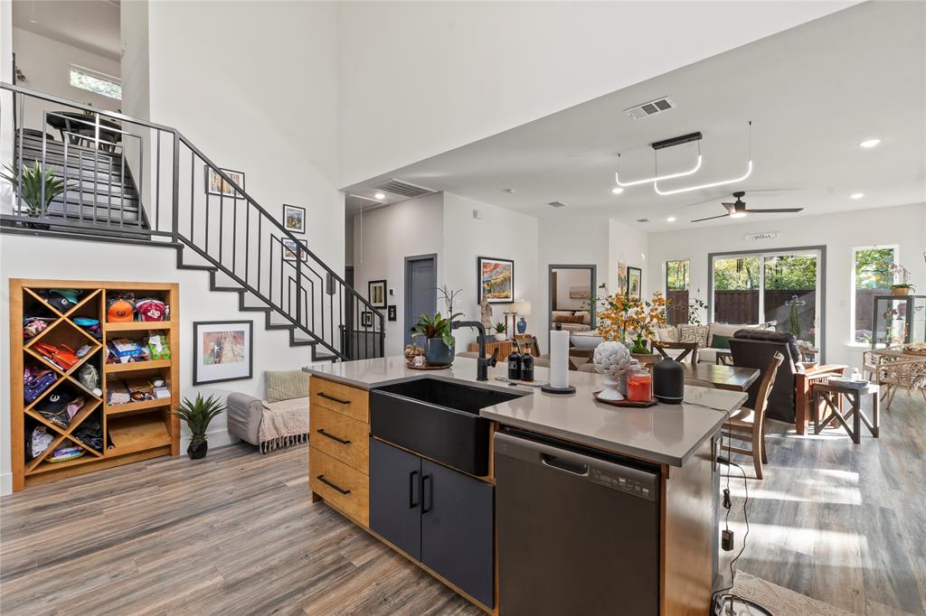 Kitchen featuring an island with a quartz countertop, black farmhouse-style sink, and dual-toned cabinetry Kitchen featuring an island with a quartz countertop, black farmhouse-style sink, and dual-toned cabinetry