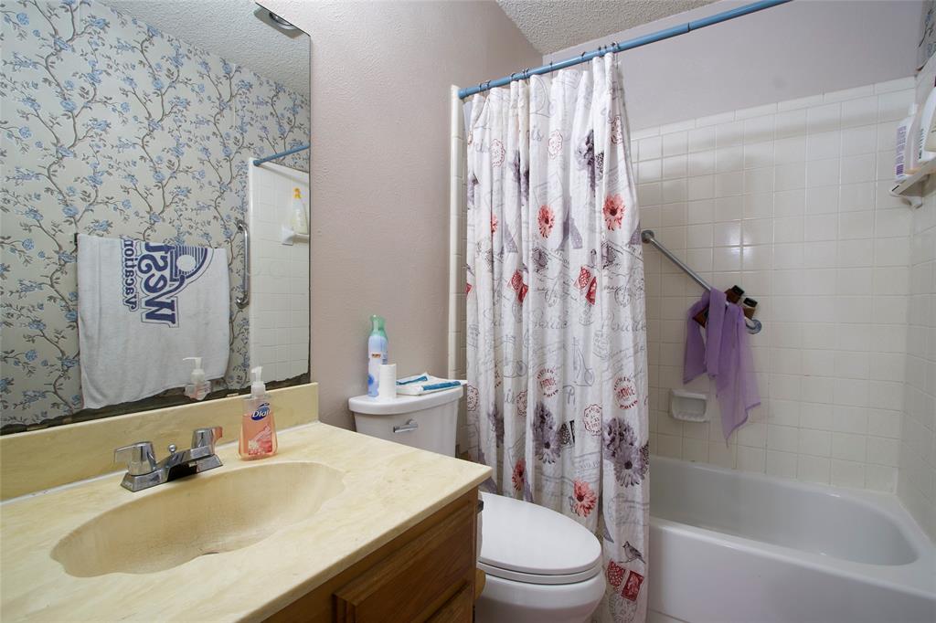 Bathroom featuring a vanity with an integrated sink and countertop, a wall-mounted mirror, and a tub-shower combination with ceramic tile surround
