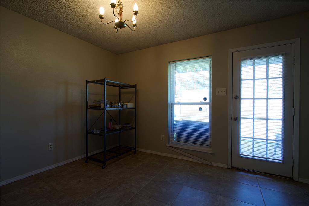 Multi-pane glass-panel exterior door, neutral tile flooring, and overhead multi-arm chandelier lighting