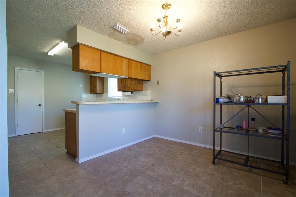 Kitchen area featuring wood cabinetry, ceramic tile flooring, a peninsula counter, and a multi-arm chandelier