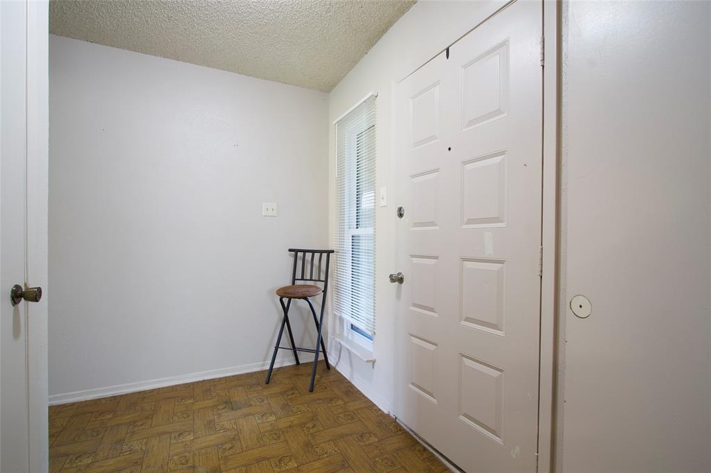 Entryway featuring parquet wood-finish flooring, a six-panel door with metallic hardware, a vertically oriented window with horizontal blinds, and a textured ceiling