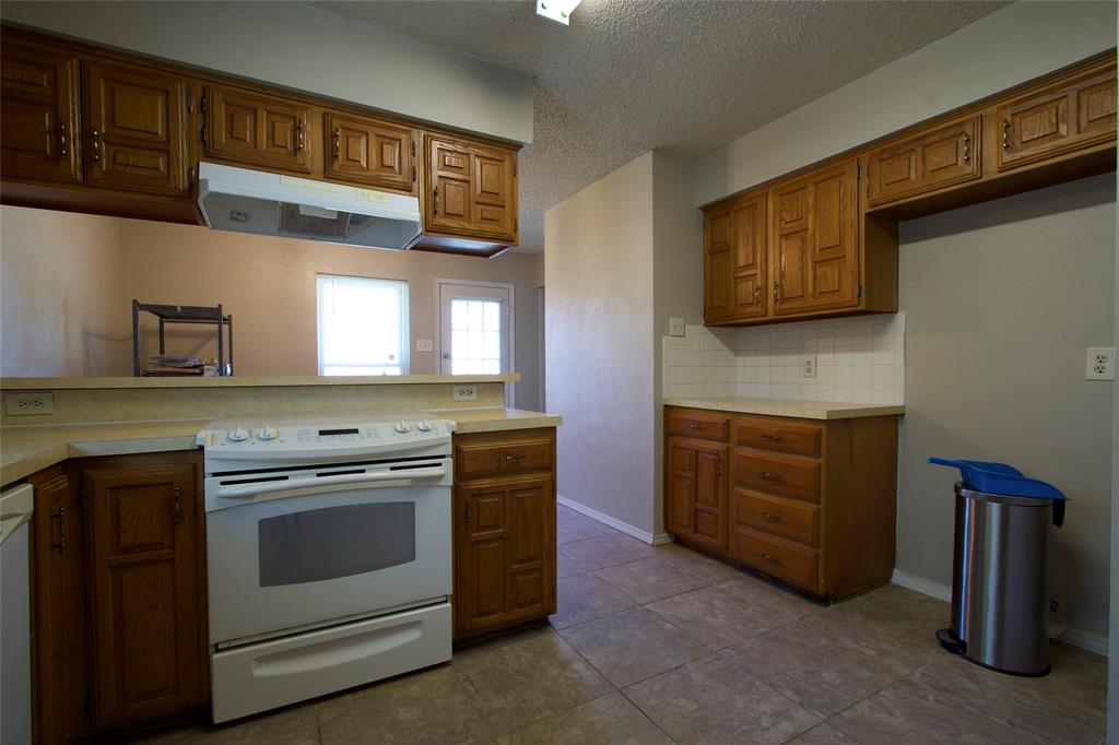 Kitchen featuring wood cabinetry, tile flooring, stone-finish countertops, and a white range