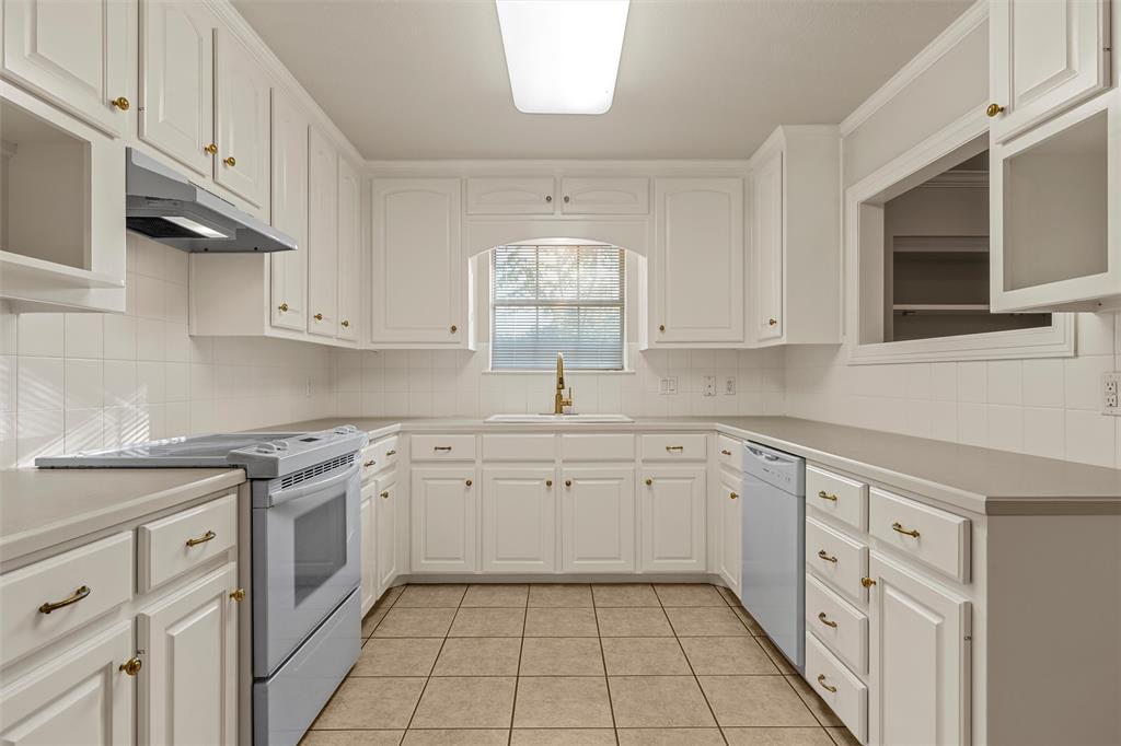 Kitchen featuring white cabinetry, solid-surface countertops, tile flooring, ceramic tile backsplash, and an arched window over the sink Kitchen featuring white cabinetry, solid-surface countertops, tile flooring, ceramic tile backsplash, and an arched window over the sink