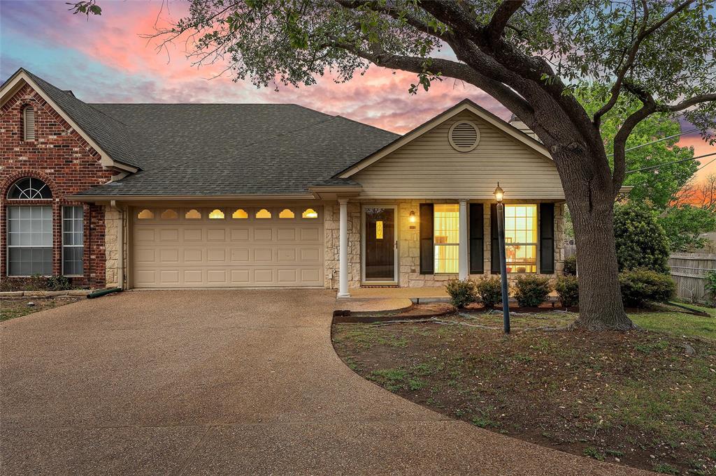 Multi-textured exterior facade featuring red brick, stone masonry, and horizontal siding, combined with a multi-gabled roofline, an arched window detail, and an aggregate concrete driveway Multi-textured exterior facade featuring red brick, stone masonry, and horizontal siding, combined with a multi-gabled roofline, an arched window detail, and an aggregate concrete driveway