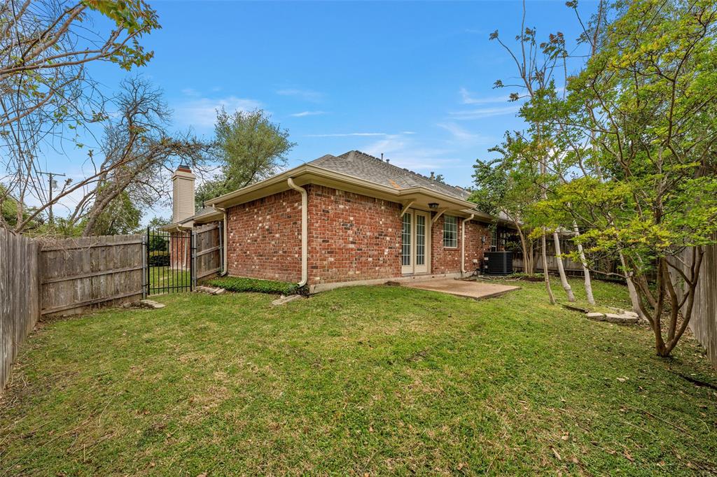 Brick exterior featuring a concrete patio, wood fencing, and mature landscaping