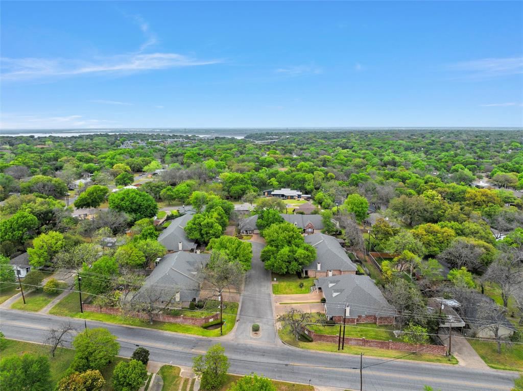 Aerial perspective featuring asphalt roadways, brick perimeter walls, mature trees, and shingled roof structures