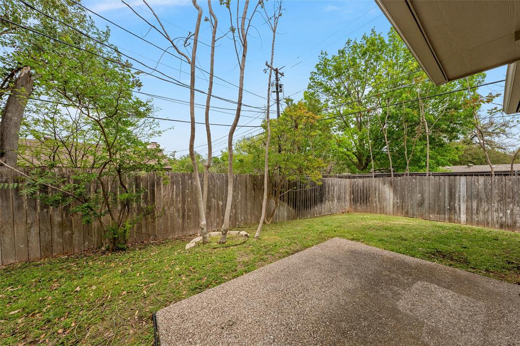 Backyard featuring a concrete patio, wood privacy fencing, and mature trees