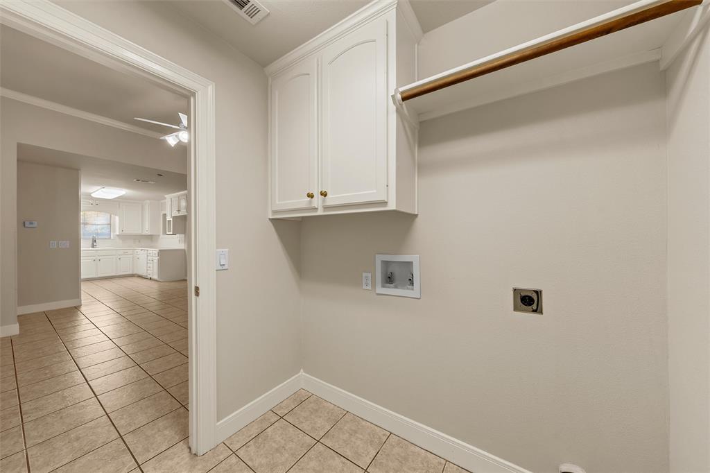 Utility area featuring neutral tile flooring, white shaker-style cabinetry, and a built-in hanging rod Utility area featuring neutral tile flooring, white shaker-style cabinetry, and a built-in hanging rod