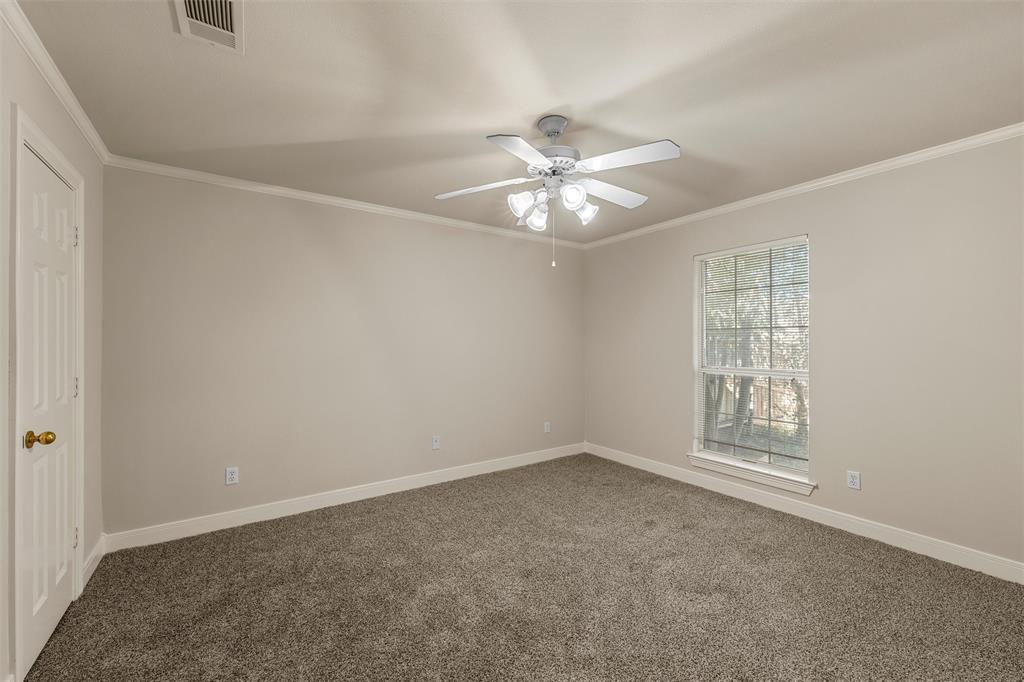 Neutral-toned interior featuring wall-to-wall carpeting, a multi-blade ceiling fan with integrated lighting, and a single-hung window with a grid pattern