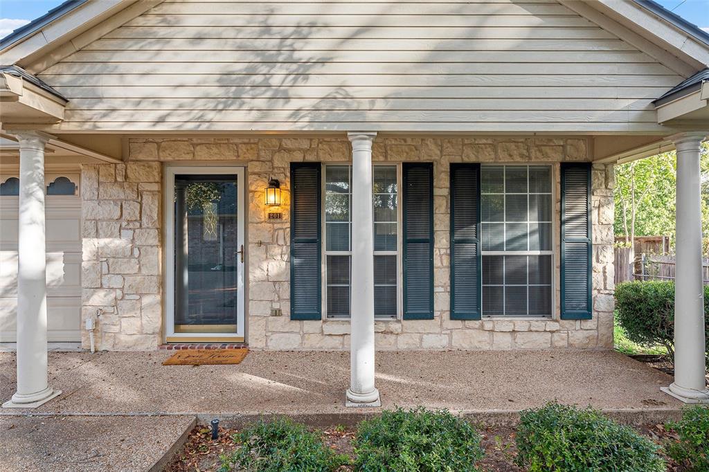 Covered front porch featuring a stone facade, decorative columns, exterior shutters, and horizontal siding Covered front porch featuring a stone facade, decorative columns, exterior shutters, and horizontal siding
