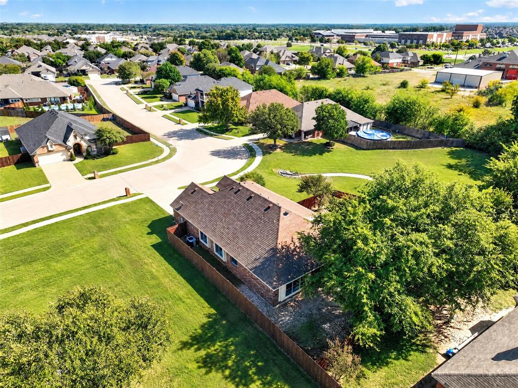 Aerial perspective of a brick exterior residence featuring a multi-gable roofline, wood-privacy fencing, and mature trees situated on a corner lot