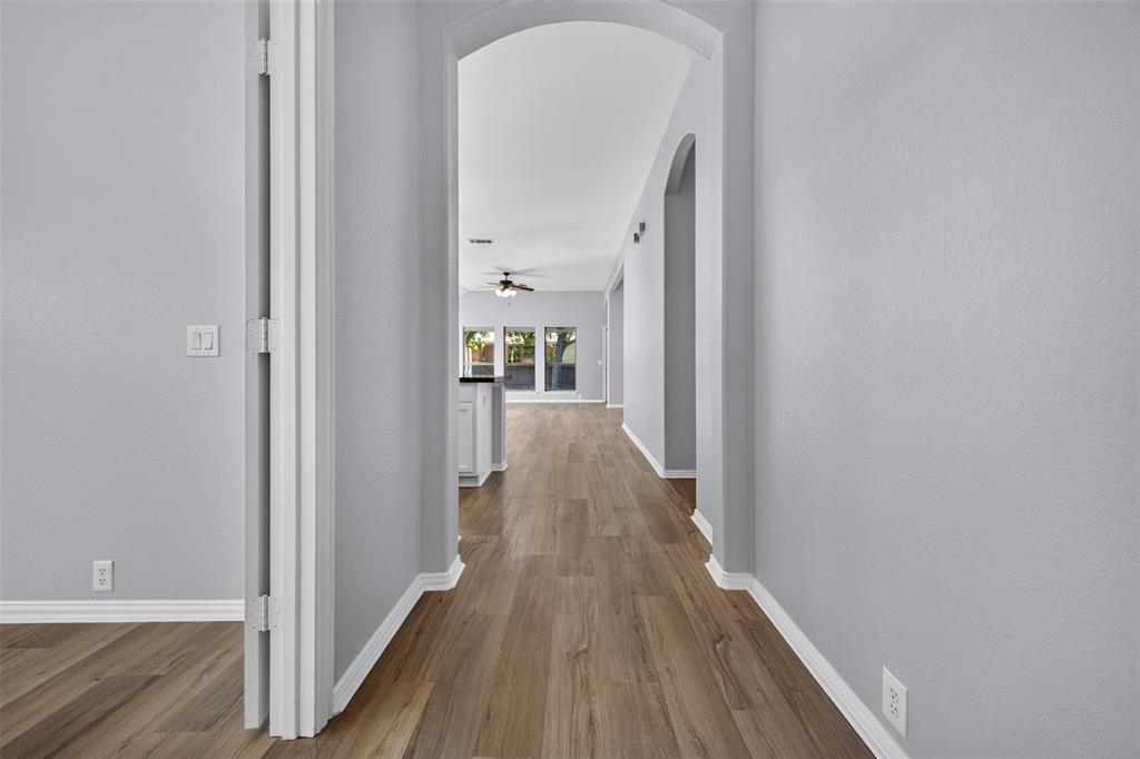 Interior hallway featuring arched architectural entryways, neutral-toned walls, and wood-finish flooring