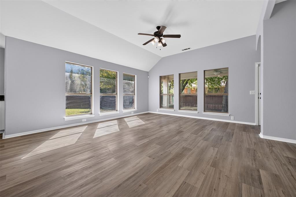Vaulted ceiling, wood-finish flooring, six large windows, and a multi-blade ceiling fan with integrated lighting