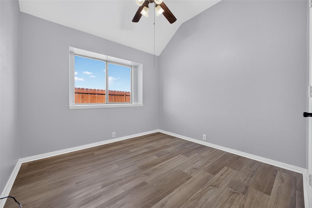 Interior space featuring vaulted ceilings, wood-finish flooring, and a ceiling fan with integrated lighting