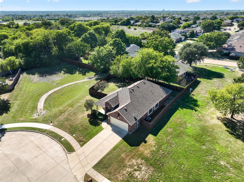 Single-story brick residence with an attached two-car garage, concrete driveway, wood privacy fencing, and expansive grounds