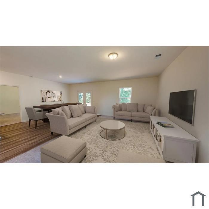 Open-concept room featuring wood-finish flooring, neutral walls, recessed lighting, and double-door rear access