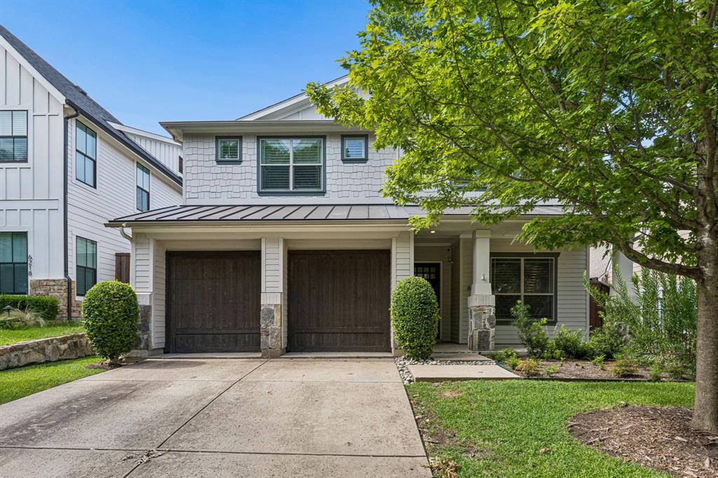 Two-story residence featuring a metal roof accent, horizontal siding, shake shingle siding, a two-car garage, and stone masonry exterior detailing