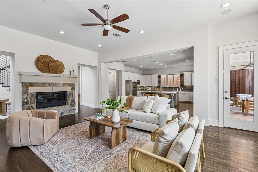Living area featuring wood-finish flooring, stone-surround fireplace, recessed lighting, and a brushed nickel ceiling fan