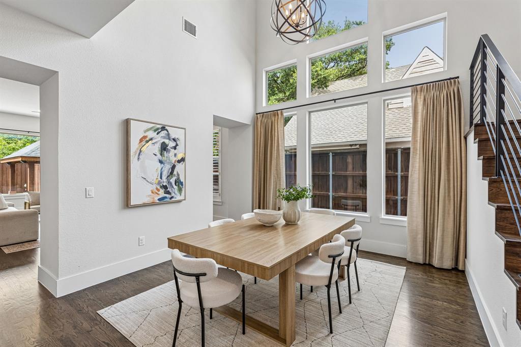 Double-height ceiling, tiered windows, wood-finish flooring, and architectural staircase with metal railing and wood treads
