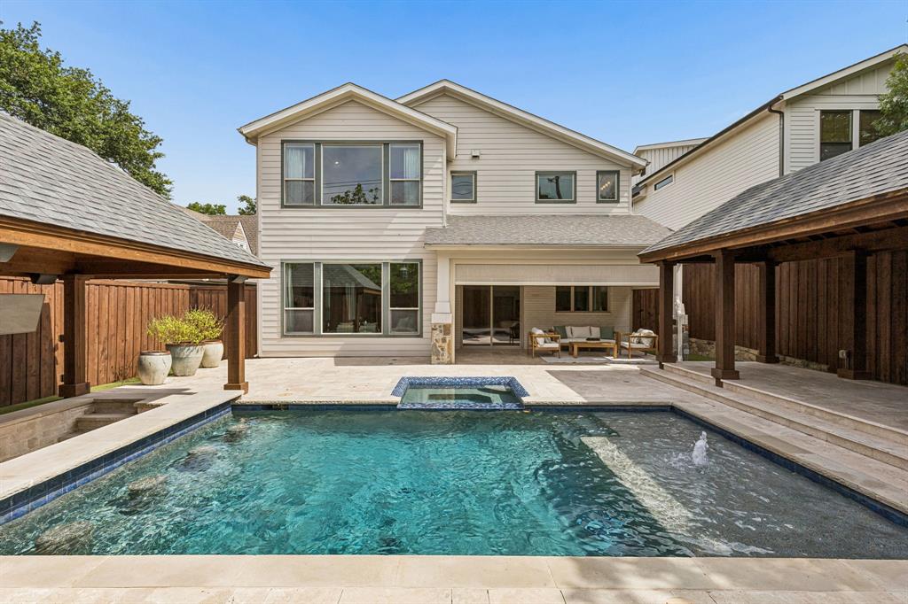Rear exterior featuring a swimming pool with a built-in spa, dual timber-framed covered patios, and stone-paver hardscaping