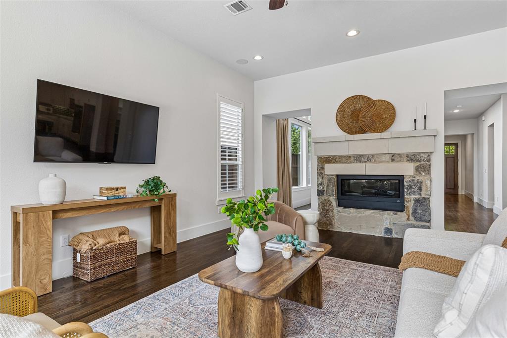Living area featuring dark wood-finish flooring, recessed lighting, and a floor-to-ceiling stone fireplace surround with a custom masonry mantel
