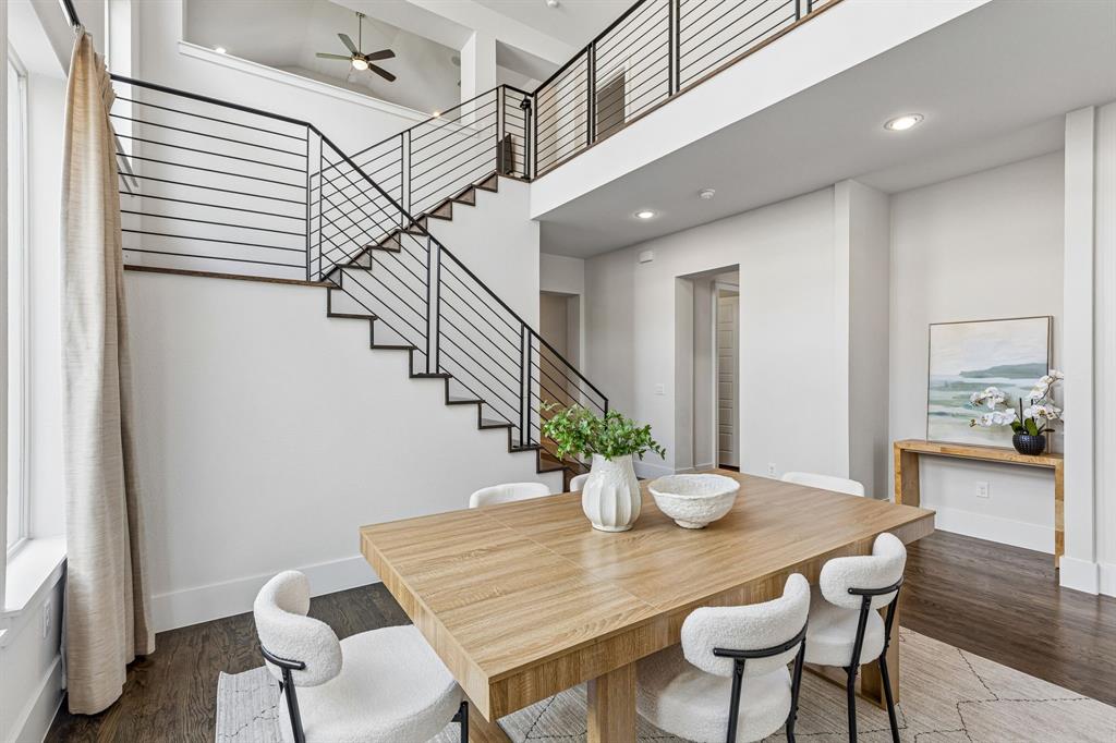 Double-height ceiling, open staircase with horizontal metal railing, wood-finish flooring, and recessed lighting