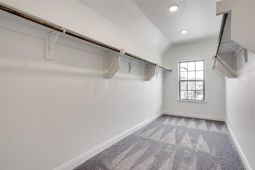 Walk-in closet featuring patterned carpeting, dual-tiered built-in shelving with hanging rods, recessed lighting, and a multi-pane window