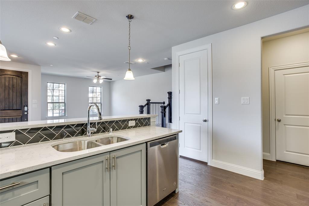 Kitchen featuring a stone-look countertop, chevron-pattern tile backsplash, stainless steel dishwasher, wood-finish flooring, and recessed lighting