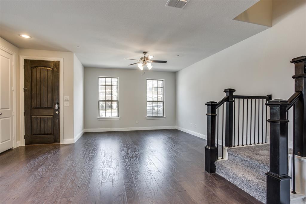 Interior space featuring dark wood-finish flooring, two multi-pane windows, a ceiling fan with integrated lighting, and a staircase with a dark-finished handrail and metal balusters Interior space featuring dark wood-finish flooring, two multi-pane windows, a ceiling fan with integrated lighting, and a staircase with a dark-finished handrail and metal balusters