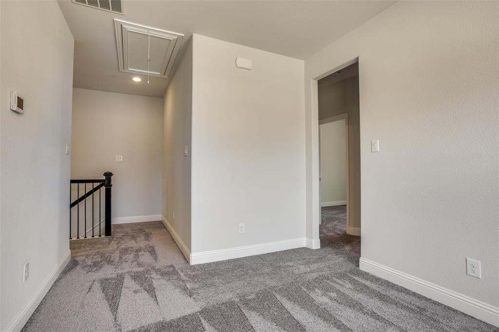 Neutral-toned carpeting, matte black spindle stair railing, and ceiling attic access panel