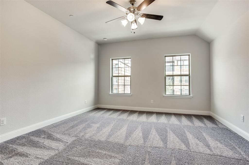 Interior room featuring neutral wall tones, patterned carpeting, dual windows, and a multi-light ceiling fan