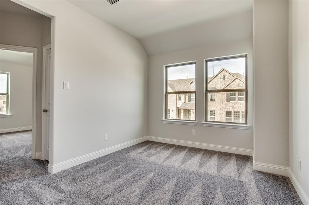 Neutral-toned interior space featuring neutral carpeting, a slanted ceiling, and dual-pane windows with trim