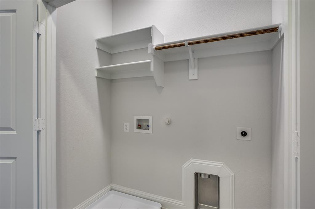 Built-in white shelving with integrated hanging rod, recessed wall-mounted utility connections, and metallic recessed floor box